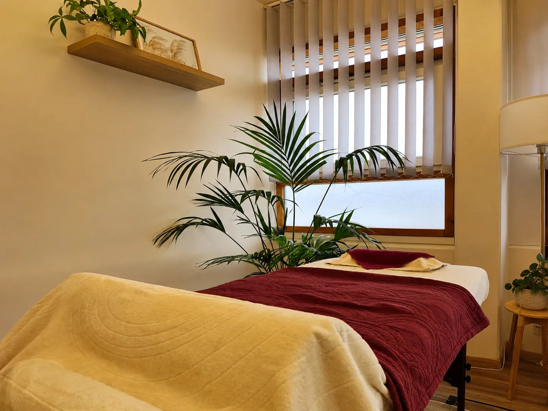 Warmer Aroma-Massageraum bei Olvenia mit Massageliege, Pflanzen und beruhigender Wellness-Atmosphäre
